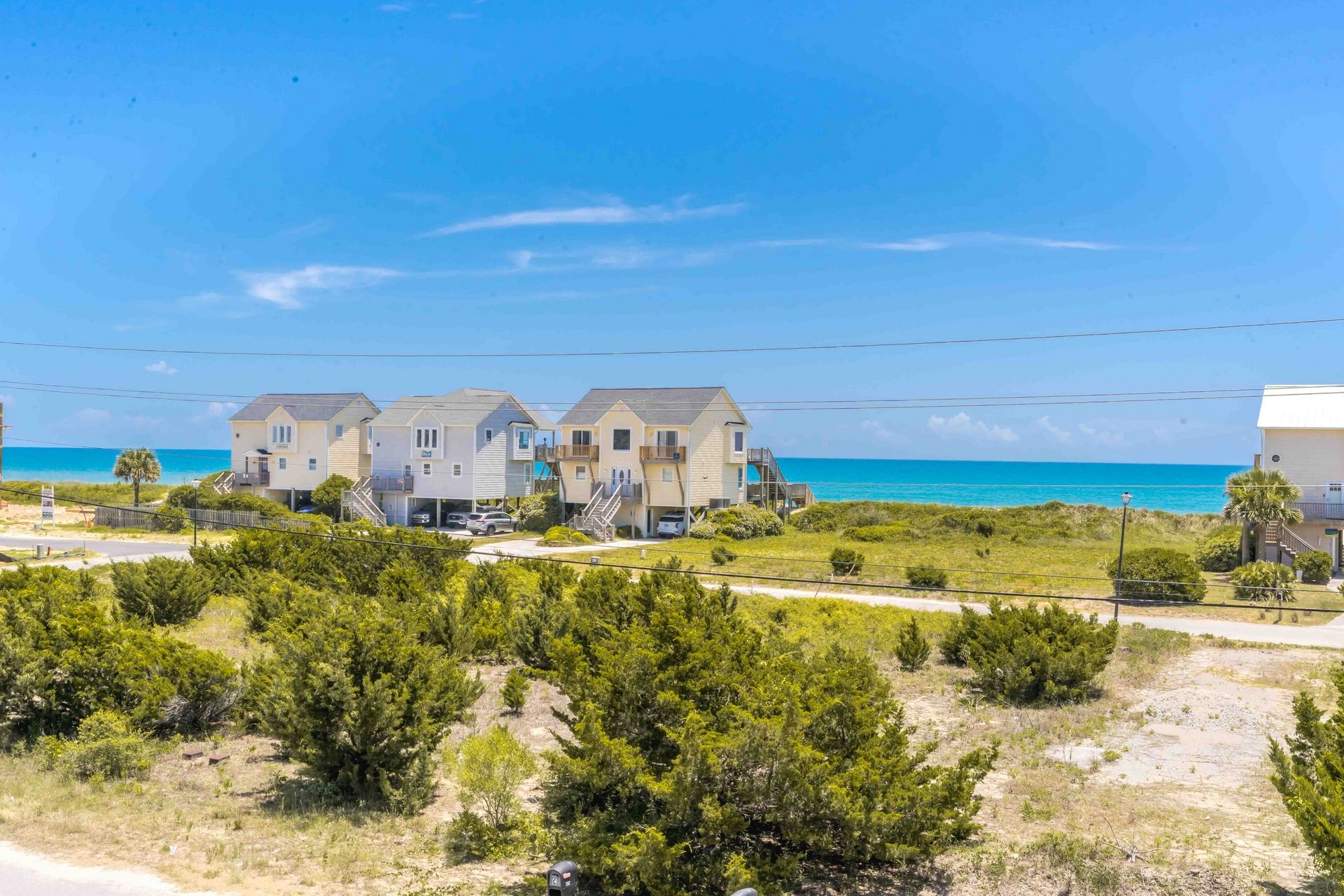 Une propriété située en bord de mer, comprenant plusieurs maisons, offrant une vue dégagée sur l’océan et dotée d’une pelouse bien entretenue.