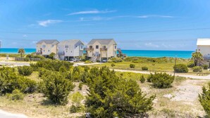 A beachfront property with multiple houses, a clear view of the ocean, and a well-maintained lawn.