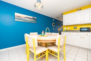 A kitchen with white cabinets, a microwave, and a dining area with a table and chairs. - Mermaid's Hive - 3 BR Townhouse with Ocean Views; Dog Friendly! (Surf City)