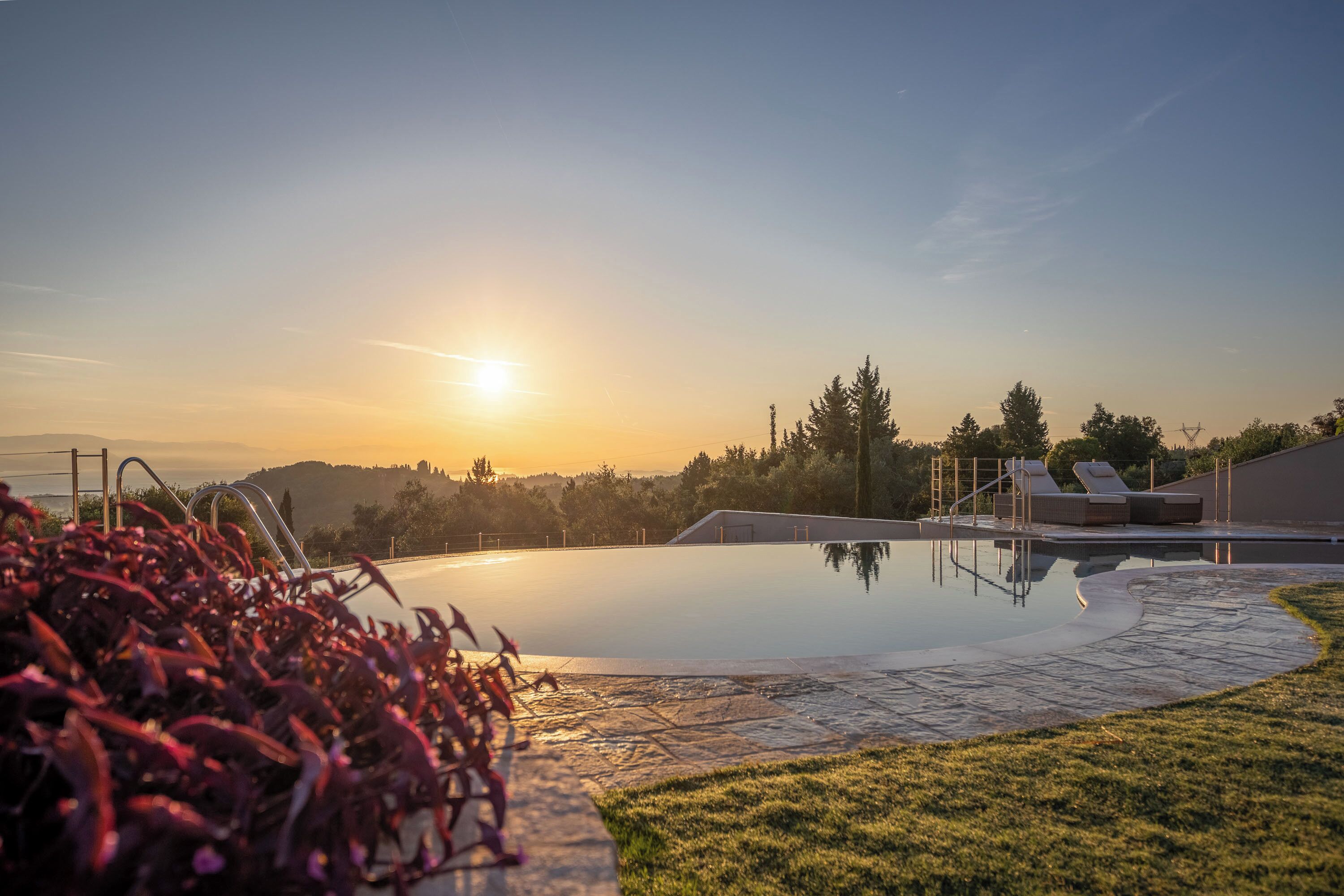 Una piscina amb una vista clara del capvespre, envoltada d'una gespa cuidada i unes quantes gandules.