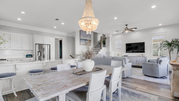 A modern kitchen with white cabinetry, a large dining table, and a chandelier. - Flash Sale! Charming home in Orange Beach, AL (Orange Beach)