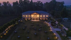 A large, two-story building with a covered patio area and multiple outdoor seating arrangements. - Vanashraya corbett (Kaladhungi)