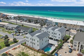 A beachfront hotel with multiple-story buildings, a swimming pool, and a beach view.
