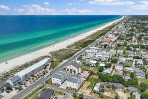 Vue aérienne d’une ville côtière avec une plage, des immeubles résidentiels et une route.