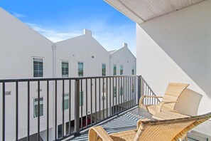 Un balcon avec des fauteuils en osier et une vue sur des bâtiments blancs.