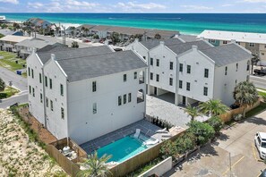 Un immeuble résidentiel doté d’une piscine, situé près d’une plage aux eaux bleues et cristallines.