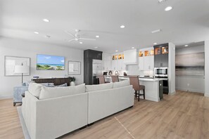 Une cuisine moderne avec des armoires blanches, un four à micro-ondes encastré et un grand îlot central.