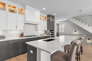 Une cuisine moderne dotée d’un plan de travail en marbre, de meubles gris et d’un îlot central avec des tabourets de bar.