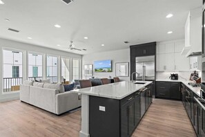 Una cucina moderna con isola centrale, mobili scuri e una grande finestra con vista sulla città.