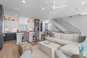 Une cuisine moderne avec des meubles blancs, un îlot central et un coin repas avec des chaises.