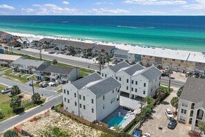 A coastal residential area with beachfront properties, a swimming pool, and a clear view of the ocean.