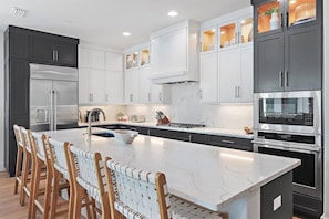 A modern kitchen with a large island, stainless steel appliances, and a mix of dark and light cabinetry.