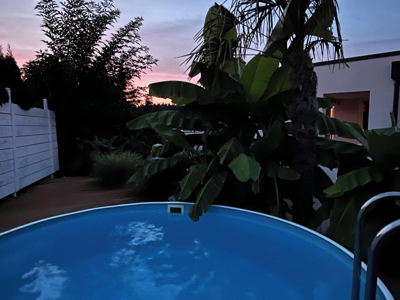 Ein Schwimmbad, umgeben von Grünflächen und einem weißen Zaun.