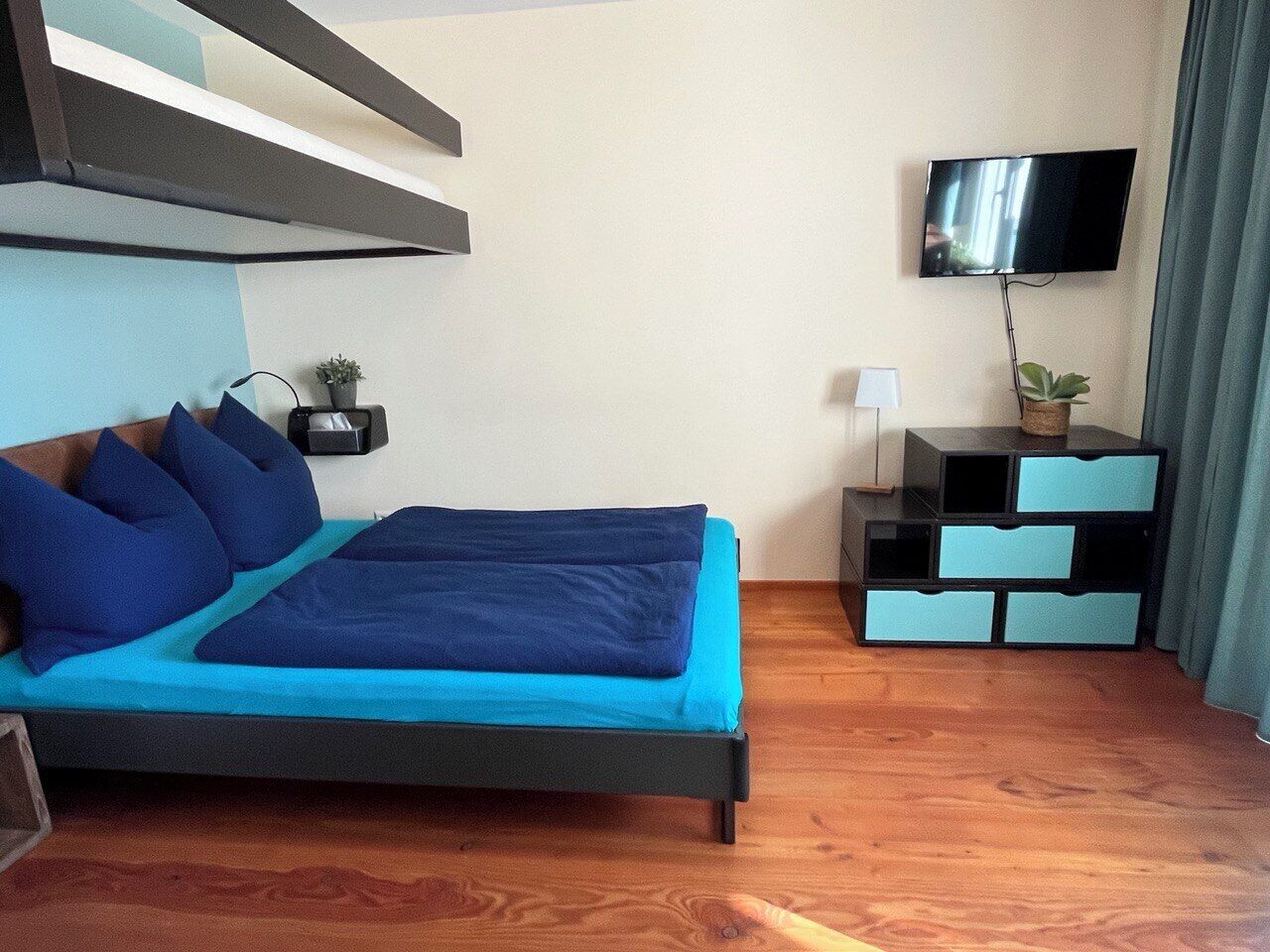 Ein modernes Schlafzimmer mit einem Bett, einem Fernseher und einem Nachttisch mit Schubladen.