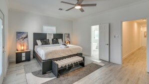 A bedroom with a bed, nightstands, a ceiling fan, and a door leading to another room. - 4 Mi to NRG Stadium: Luxurious Houston Townhome! (Houston)