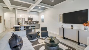 A modern living room with a grey sofa, black accent pillows, a round coffee table, and a flat-screen TV mounted on the wall. - 4 Mi to NRG Stadium: Luxurious Houston Townhome! (Houston)