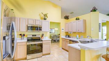 A modern kitchen with light-colored cabinets, stainless steel appliances, and a central island with a sink.