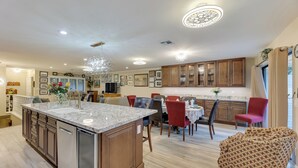 A spacious kitchen with a large island, wooden cabinets, and a dining area with red chairs. - Golf, Hike, Swim: Your Perfect Desert Oasis Escape (Mesa)