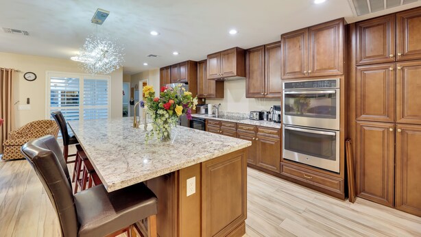 A modern kitchen with wooden cabinets, a marble island, and stainless steel appliances. - Golf, Hike, Swim: Your Perfect Desert Oasis Escape (Mesa)