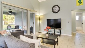 Ein Wohnzimmer mit einer Couch, einem Couchtisch, einem Fernseher und einer Wanduhr.