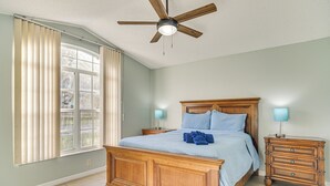 Ein Schlafzimmer mit einem großen Bett, zwei Nachttischen, einem Deckenventilator und einem Fenster mit Vorhängen.