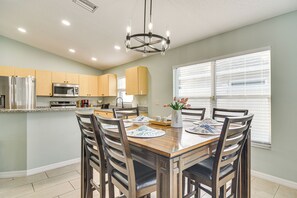Una cocina moderna con una isla central, electrodomésticos de acero inoxidable y un comedor con mesa y sillas de madera.