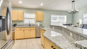 Eine moderne Küche mit Granit Arbeitsplatten, Edelstahlgeräten und hellgrünen Wänden.