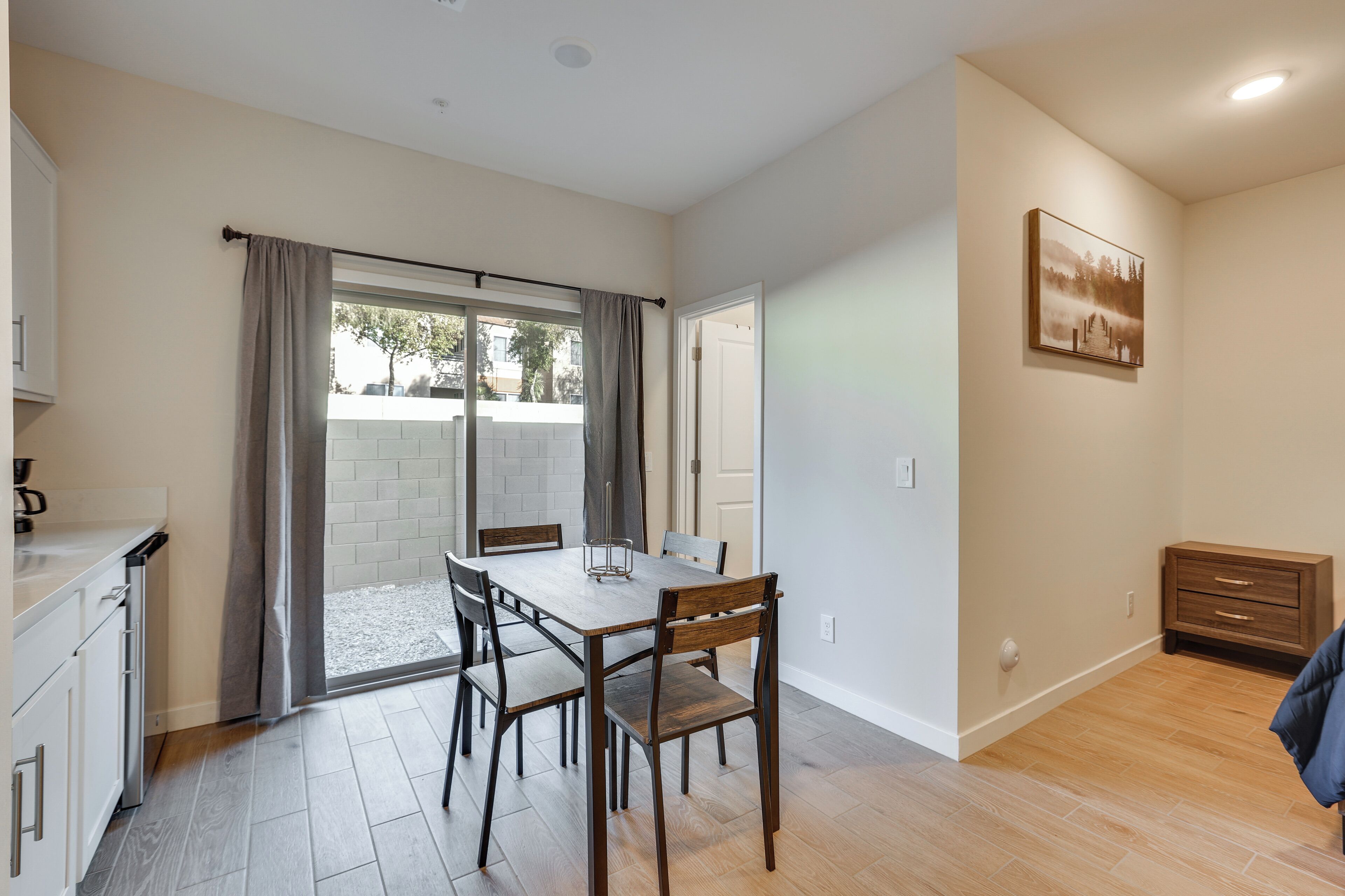 A dining area with a table and chairs, a kitchen with cabinets, and a sliding glass door leading to an outdoor patio.