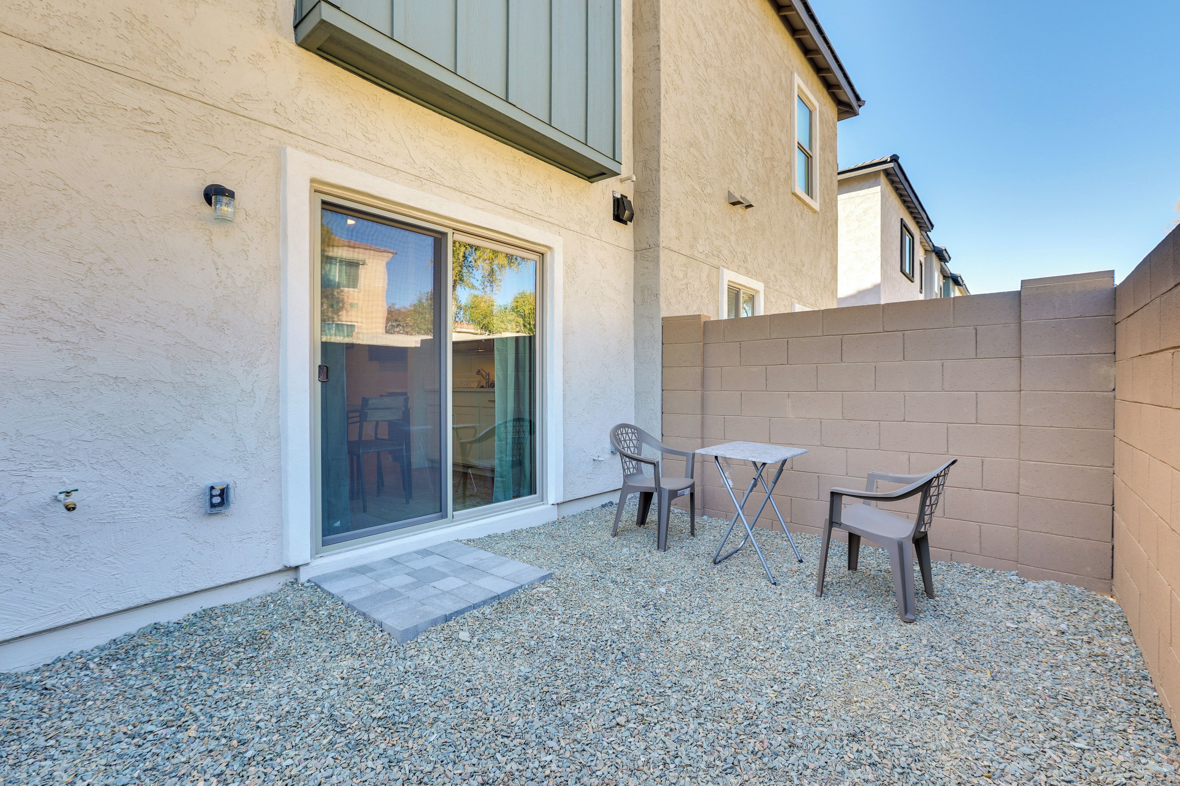 A patio area with a table and chairs, a sliding glass door, and a small step leading to a covered entrance.
