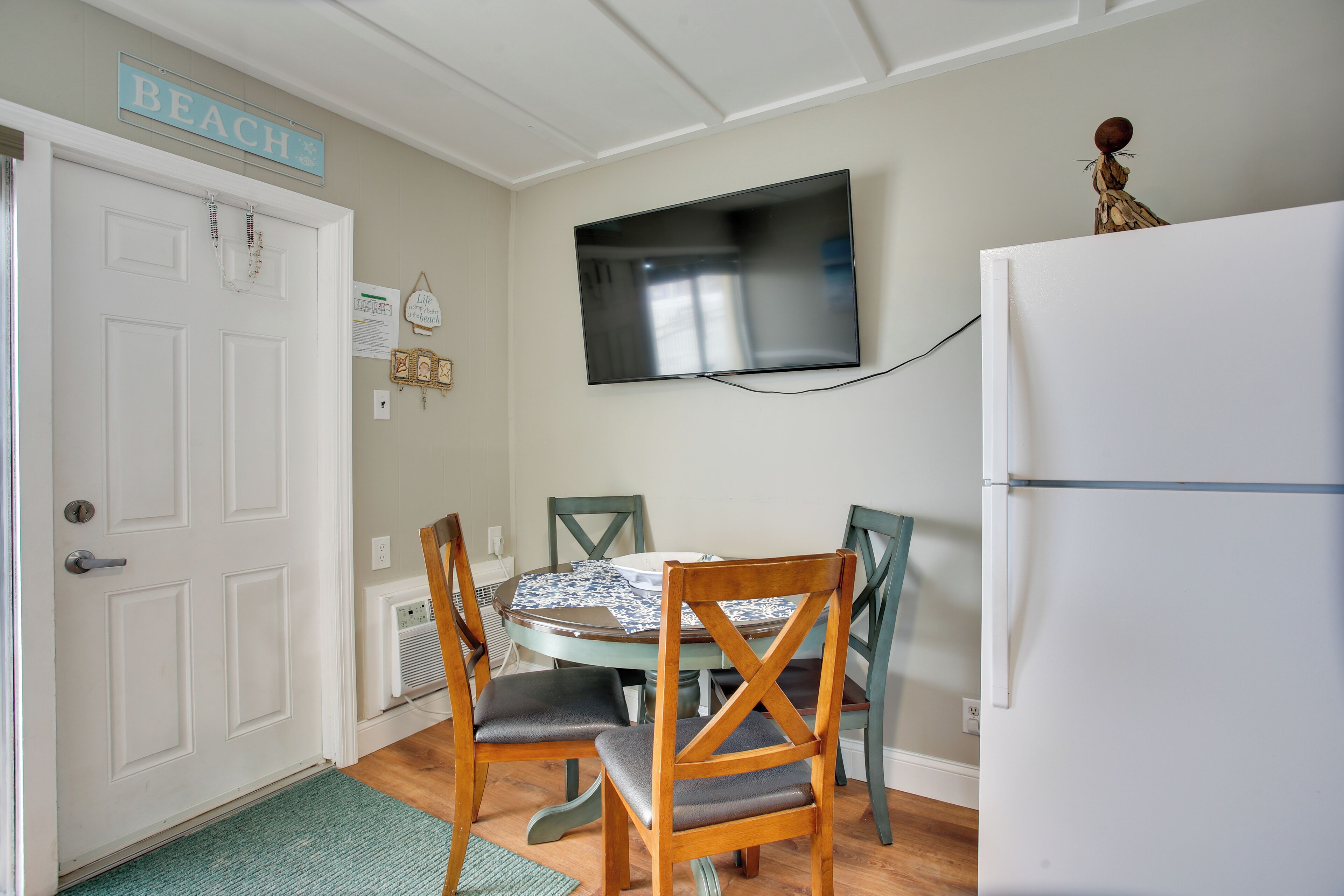 A dining area with a table, chairs, a television, and a refrigerator.