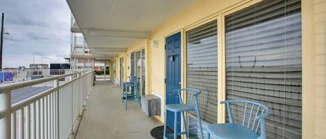 A covered balcony with blue chairs and a blue door, overlooking a dock area.