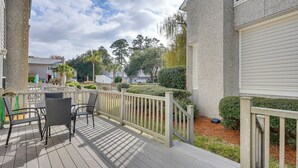 A wooden deck with outdoor furniture, a white railing, and a view of neighboring houses and trees. - 3 Mi to St Simons Beach: Gem w/ Pool Access & Deck (St. Simons Island)