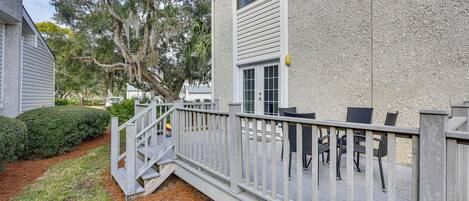 A covered patio with outdoor furniture, a white railing, and a small staircase leading to the house.