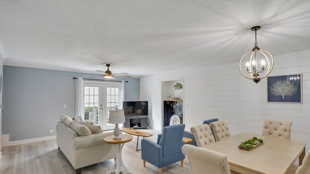 A living room with a sofa, armchairs, a dining table, and a chandelier. - 3 Mi to St Simons Beach: Gem w/ Pool Access & Deck (St. Simons Island)