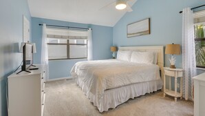 A bedroom with a bed, ceiling fan, window with curtains, bedside lamps, and a dresser. - 3 Mi to St Simons Beach: Gem w/ Pool Access & Deck (St. Simons Island)