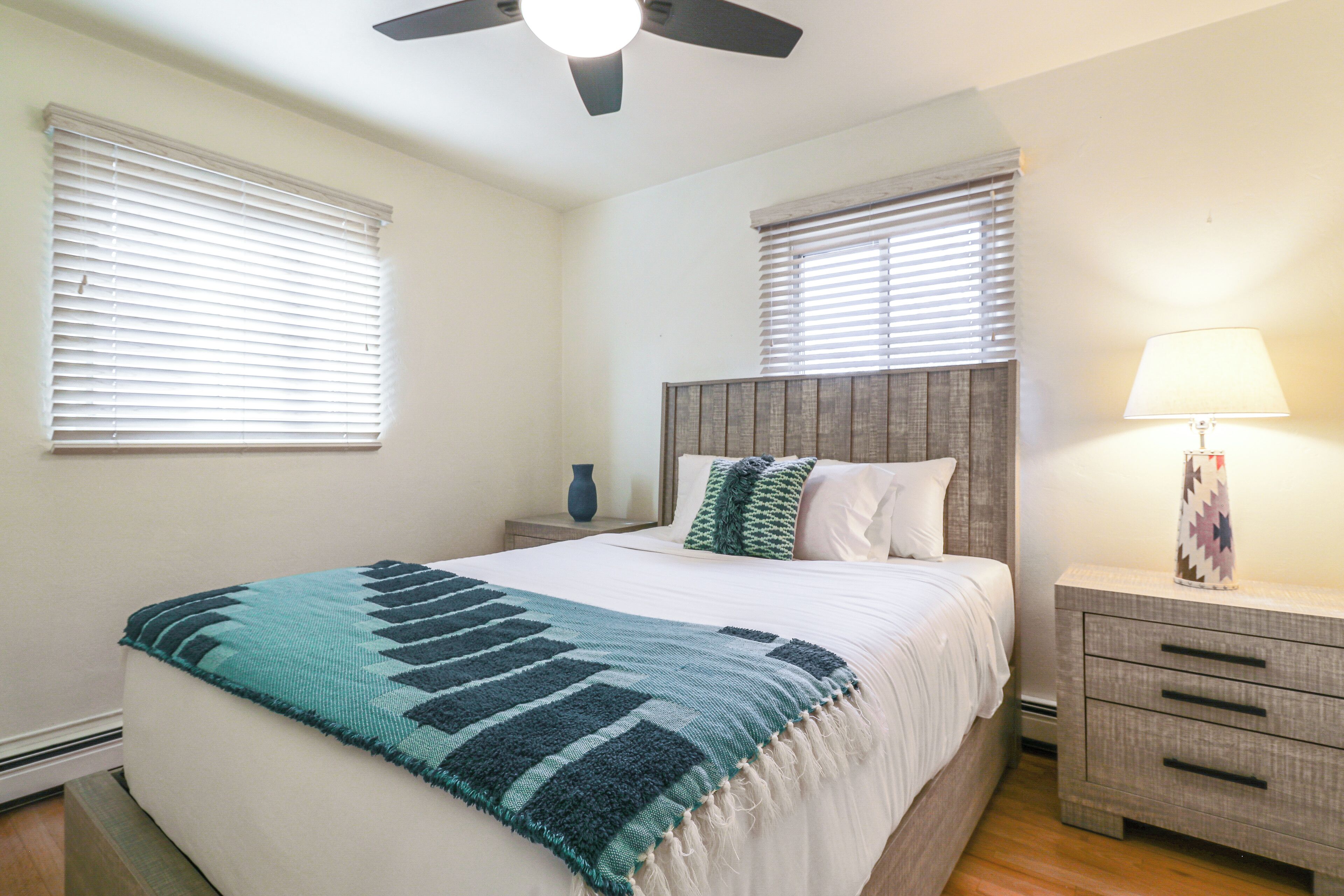 A bedroom with a bed, nightstands, a lamp, and a ceiling fan.