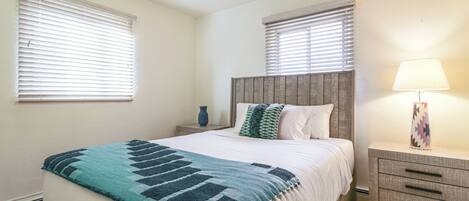 A bedroom with a bed, nightstands, a lamp, and a ceiling fan.