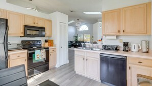 A modern kitchen with wooden cabinets, stainless steel appliances, and a central island. - 6 Mi to Disney World: Home w/ Large Yard! (Kissimmee)
