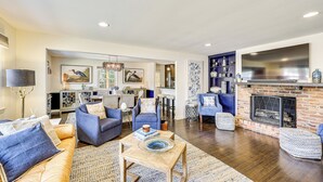 A spacious living room with a fireplace, blue upholstered chairs, and a dining area in the background. - Walk to Powderhouse Polo Fields: Aiken Getaway (Aiken)