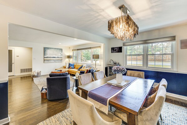 A spacious living area with a dining table, comfortable seating, and large windows providing natural light.