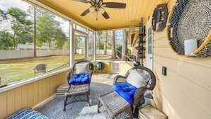A covered porch with wicker furniture, a ceiling fan, and large windows offering a view of the backyard. - Walk to Powderhouse Polo Fields: Aiken Getaway (Aiken)