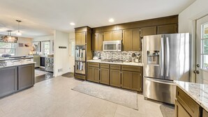 A modern kitchen with stainless steel appliances, wooden cabinets, and a large island with a marble countertop. - Walk to Powderhouse Polo Fields: Aiken Getaway (Aiken)