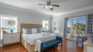 A spacious bedroom with a large bed, a ceiling fan, and a balcony with a view. - Luxurious Oceanfront Home w/ Soaring Views + Private Pool by Tybee Cottages (Tybee Island)