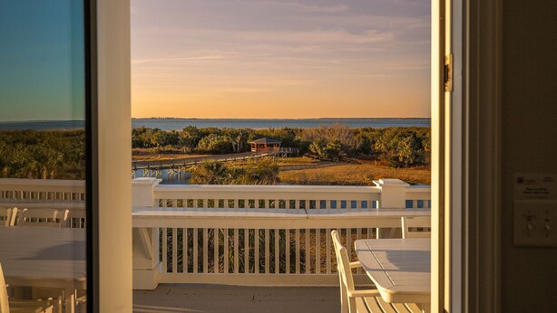 A balcony with a view of a beach and a distant building. - Luxurious Oceanfront Home w/ Soaring Views + Private Pool by Tybee Cottages (Tybee Island)