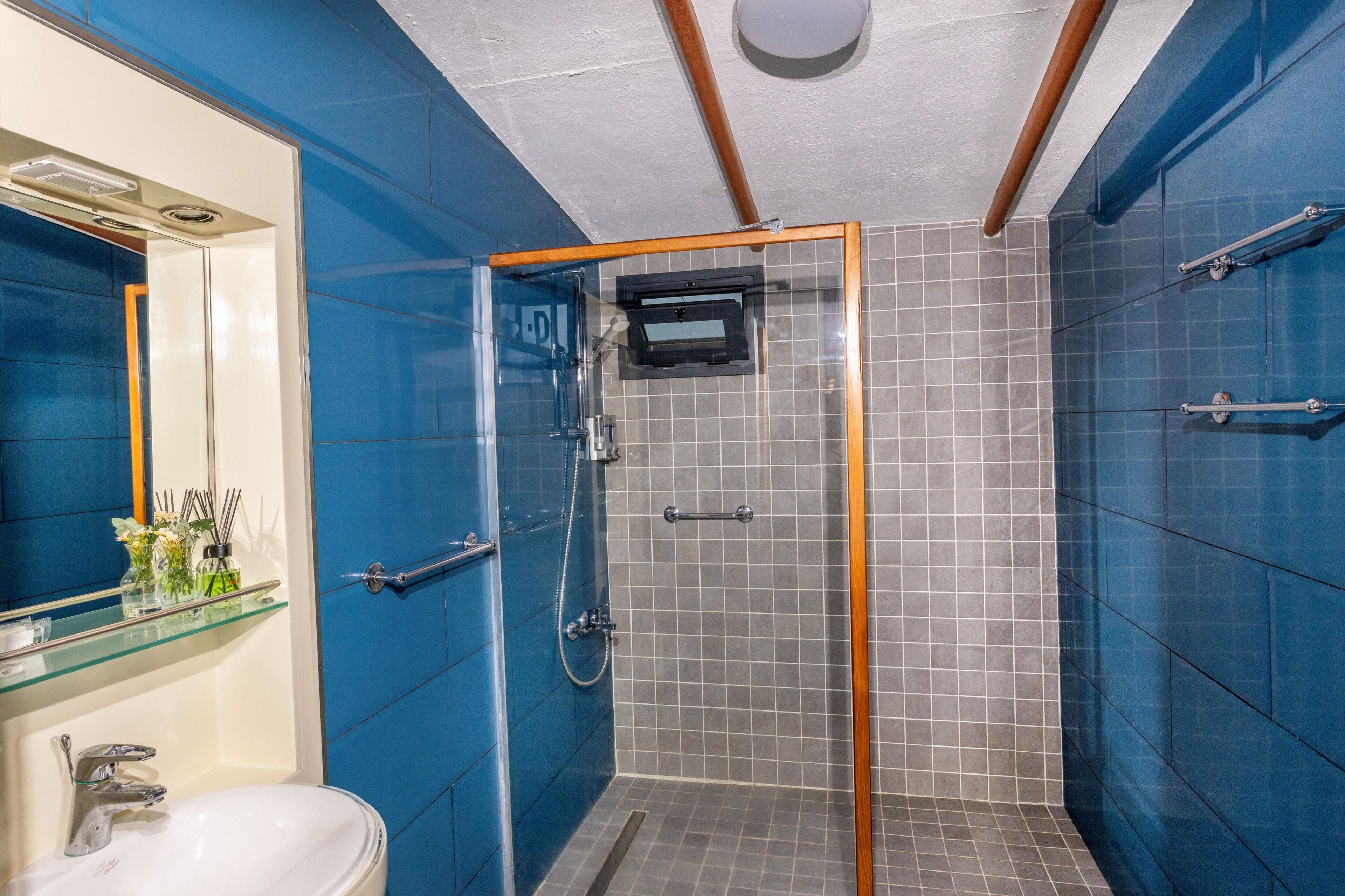 A bathroom with a glass-enclosed shower, a white sink, and a mirror.