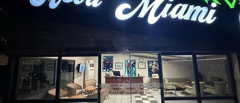 Entrada de hotel con zona de recepción, mostrador de check-in y asientos.