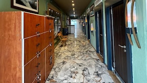 A hotel corridor with marble flooring, wooden cabinets, and doors labeled "WC MEN". - Reva Miami Hotel Restaurant SPA (Foça)