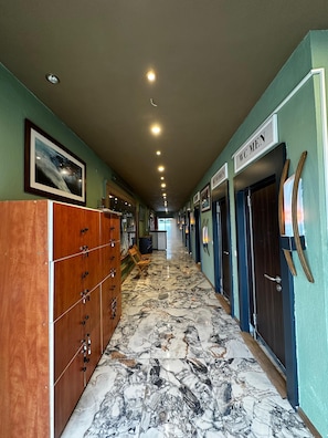 A hotel corridor with marble flooring, wooden cabinets, and doors labeled "WC MEN". - Reva Miami Hotel Restaurant SPA (Foça)