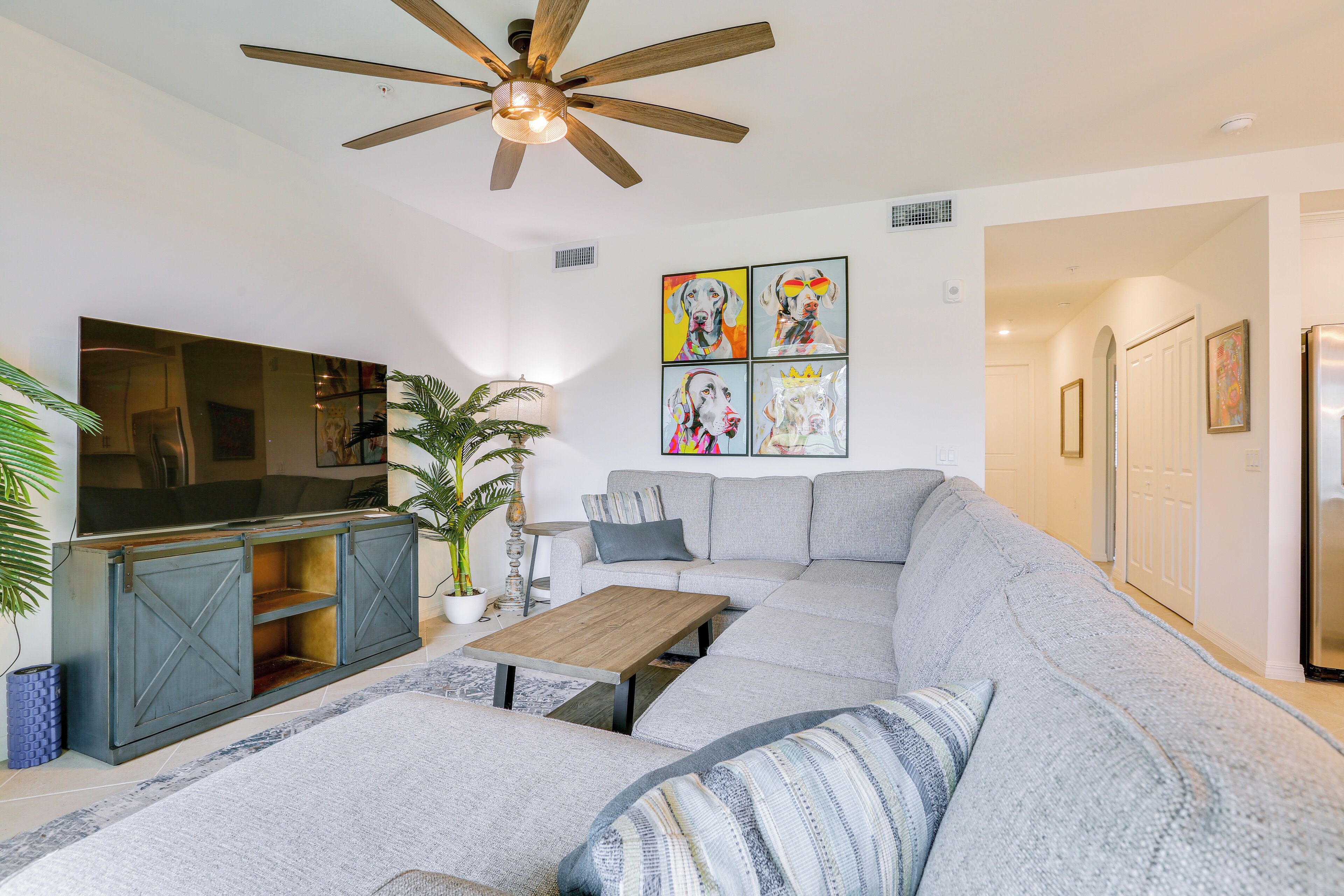 A modern living room with a sectional sofa, a wooden coffee table, and a ceiling fan.