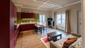 A modern kitchen with a dining area, a sofa, and a TV.